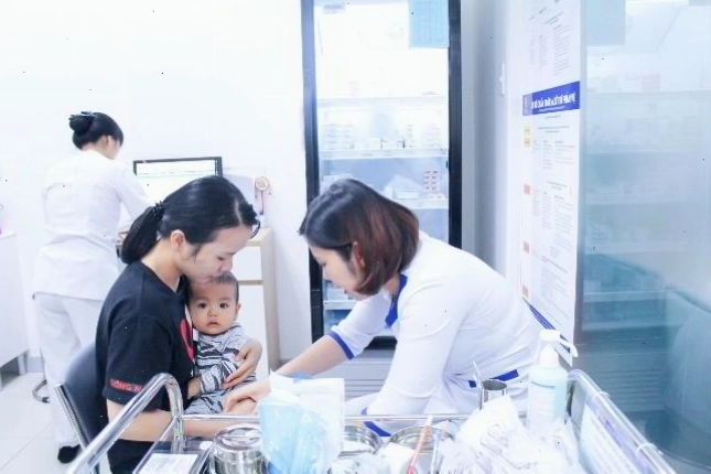 Bé đang được nhân viên y tế chuẩn bị tiêm phòng vắc xin 5 trong 1